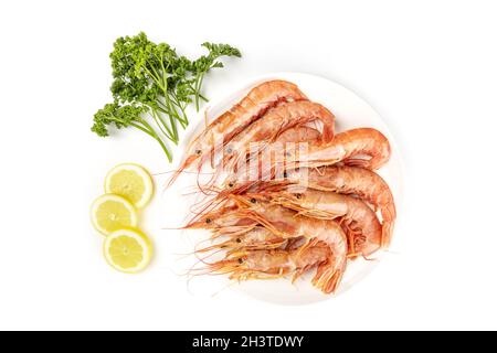 Photo aérienne d'une assiette de crevettes crues sur blanc, avec persil et citron, avec espace de copie Banque D'Images