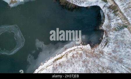 Vue aérienne de la forêt enneigée d'hiver et du lac gelé d'en haut capturé avec un drone Banque D'Images