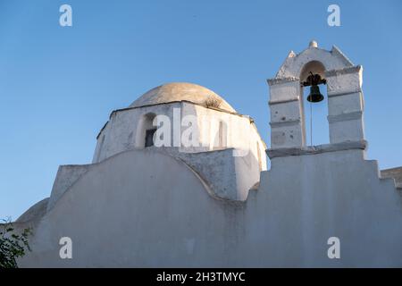 L'île de Folegandros, la vieille église dôme et le beffroi à la ville de Chora.Grèce, Cyclades.Chapelle Agios Antonios, murs blanchis à la chaux, ciel bleu clair. Banque D'Images