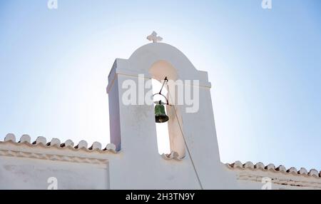 Beffroi avec ancienne cloche au toit en tuiles de l'église chrétienne orthodoxe grecque.Chapelle blanchie à la chaux sur l'île de Kythnos village de Chora Cyclades destination religieuse G Banque D'Images