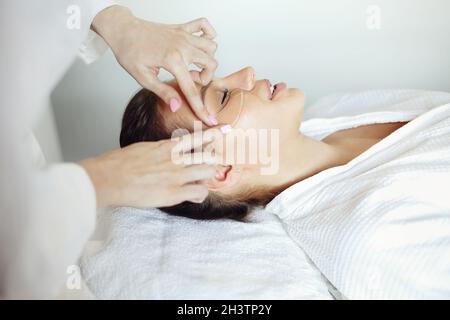 Esthéticienne appliquant des cellules oculaires sur le visage de la femme Banque D'Images