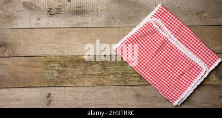 Serviette de cuisine en coton rouge et blanc sur fond gris en bois Banque D'Images