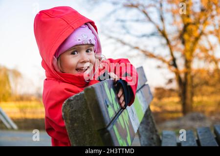 Enfant en plein air au début du printemps, suspendu sur banc dans une zone rurale. Banque D'Images