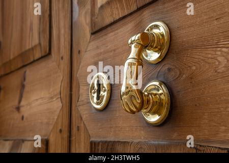 Gros plan d'un bouton doré en forme de main d'une porte en bois robuste Banque D'Images