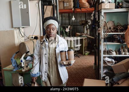 Jeune femme africaine ayant une pause à son travail, elle porte une boîte à lunch et des boissons au café Banque D'Images