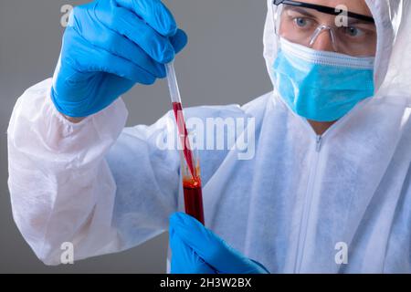 Un médecin caucasien portant un costume d'epi tenant un tube à essai Banque D'Images