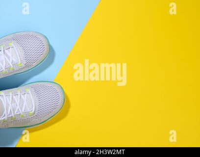 Sneakers blanches pour femme avec lacets sur fond bleu jaune Banque D'Images