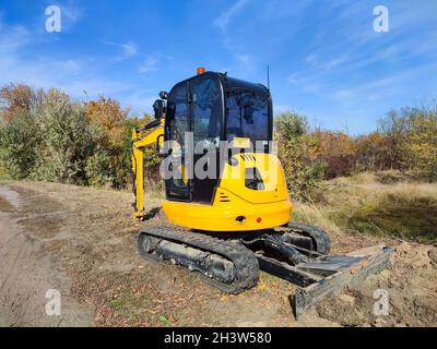 Mini-excavatrice ou excavatrice JCB jaune moderne effectue des travaux d'excavation à l'extérieur Banque D'Images