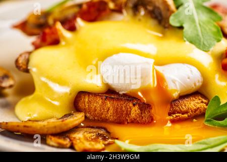 Gros plan des œufs Benedict avec sauce hollandaise et jaune d'œuf liquide Banque D'Images