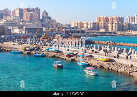 Alexandrie, Égypte - 14 décembre 2018 : vue sur la ville côtière avec bateaux de pêche.Les pêcheurs sont sur le brise-lames en béton dans le port d'Alexandrie Banque D'Images