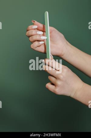 Rogner une femme qui dépose de longs ongles sur fond vert Banque D'Images