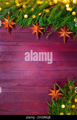 Texture des panneaux rouge et violet avec des branches de thuja vert et des étoiles orange avec bokeh jaune.Noël, nouvel an.Verticale.Copier l'espace Banque D'Images