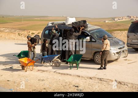 Les réfugiés syriens retournent chez eux.Les enfants qui transportent des marchandises avec des brouettes pour de l'argent les aident. Banque D'Images