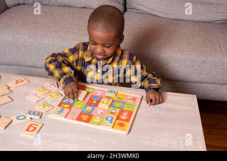 Petit garçon d'âge préscolaire à la maison jouant avec un casse-tête d'alphabet Banque D'Images