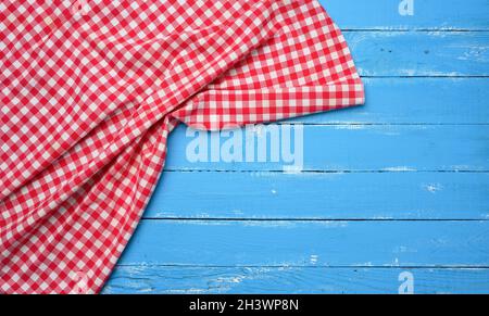 Serviette de cuisine en coton rouge et blanc sur fond de bois bleu Banque D'Images