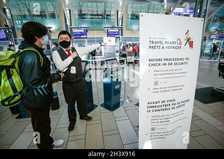 Richmond, Canada.30 octobre 2021.Un membre du personnel de la compagnie aérienne aide un voyageur au hall des départs de l'aéroport international de Vancouver, à Richmond (Colombie-Britannique), au Canada, le 30 octobre 2021.À compter du samedi, les voyageurs âgés de 12 ans ou plus doivent fournir la preuve qu'ils ont été entièrement vaccinés contre la COVID-19 lors de leurs voyages au Canada ou à l'étranger.Credit: Liang Sen/Xinhua/Alay Live News Banque D'Images