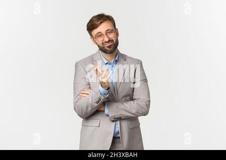 Portrait d'homme d'affaires douteux avec barbe, portant des lunettes et un costume, grimaquant et regardant sceptique, debout indécis plus Banque D'Images