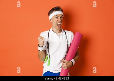 Concept d'entraînement, de gym et de style de vie.Image d'un homme de forme physique d'âge moyen motivé et heureux, atteindre l'objectif, dire oui et faire Banque D'Images