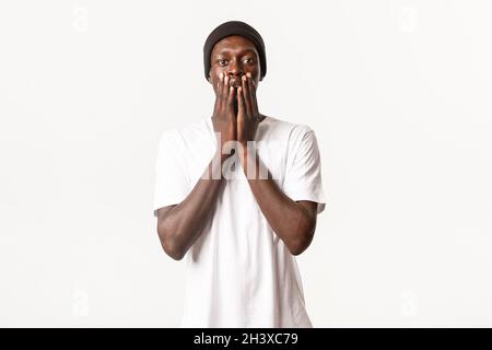 Portrait d'un homme afro-américain surpris et heureux, chanceux, gagnant et regardant étonné ou touché, debout sur le dos blanc Banque D'Images