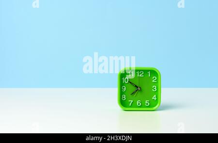 Horloge verte carrée avec des chiffres blancs sur une table blanche, de dix minutes à huit le matin Banque D'Images