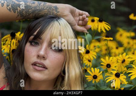 Un charmant modèle Brunette pose dans Un champ de fleurs jaunes tout en appréciant le temps d'été Banque D'Images