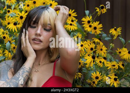 Un charmant modèle Brunette pose dans Un champ de fleurs jaunes tout en appréciant le temps d'été Banque D'Images