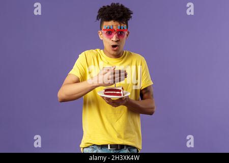 Célébration, fête et fêtes concept.Portrait de joyeux drôle, enthousiaste jeune homme célébrant l'anniversaire, protéger la candeur éclairée Banque D'Images