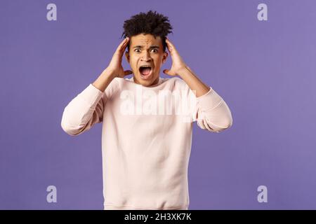 Portrait d'un jeune hispanique effrayant et anxieux dans la panique, serrer les mains nead la tête, criant et assitant la peur, bein Banque D'Images