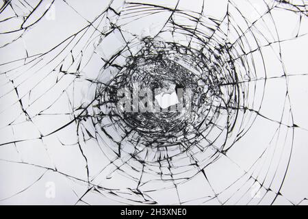 Un trou et des fissures dans un verre cassé sur une fenêtre de verre de voiture de pare-brise. Banque D'Images