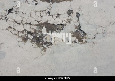 Fosses d'eau après la pluie, fissures et asphalte cassé, la route en besoin de réparation. Banque D'Images