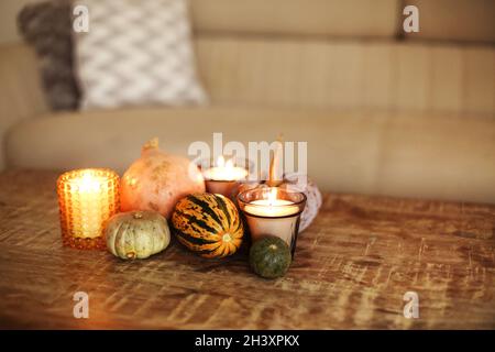 Photo de décoration d'automne ensemble de citrouilles et bougies allumées sur table basse en bois dans le salon Banque D'Images