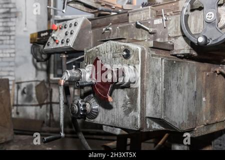 Poignée d'une ancienne fraiseuse en arrière-plan du panneau de commande dans l'atelier d'une usine industrielle. Banque D'Images