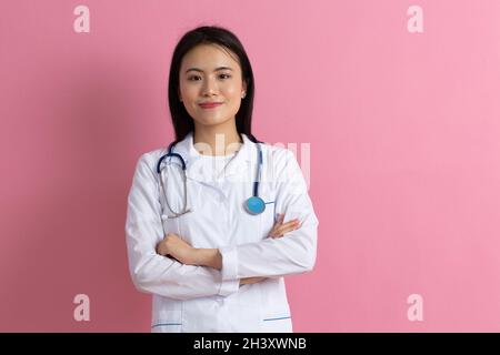 Asiatique médecin femme en robe médicale blanche avec stéthoscope contre le portrait de fond rose Banque D'Images