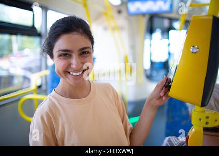 Femme de payer conctactless avec smartphone pour le transport public dans le tram Banque D'Images