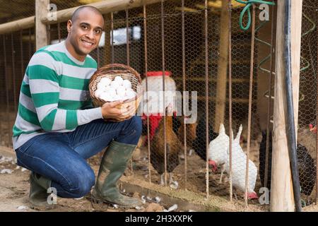 Homme souriant tient un panier d'œufs de poulet dans ses mains. Banque D'Images