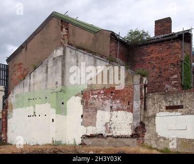 Une vieille maison abandonnée et abandonnée, avec des murs de briques en ruines, a été soutenue par des échafaudages et surcultivée avec de l'ivie Banque D'Images