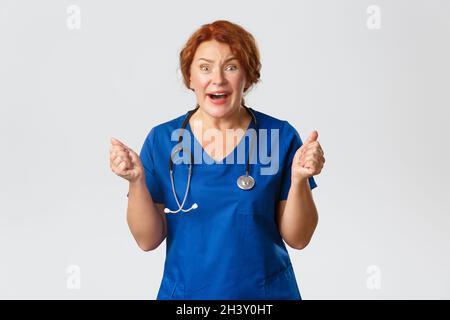 Médecine, santé et coronavirus concept.Une infirmière à tête rouge excitée, une femme médecin ou un médecin, espérons-le, regardant la caméra, le cercle Banque D'Images