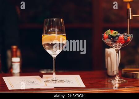 Cocktail avec citron en verre sur le bureau du bar avec menu Banque D'Images