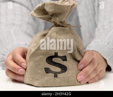 Main tient un sac de toile plein d'argent avec une icône dollar américain sur un fond blanc Banque D'Images