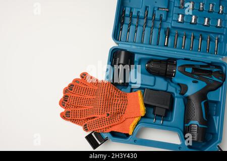 Boîte en plastique avec perceuse sans fil et jeu de forets et de tournevis sur fond blanc Banque D'Images
