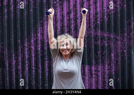 Vieux caucasien vieille femme âgée portrait gris cheveux faisant des exercices avec des haltères à l'extérieur. Banque D'Images