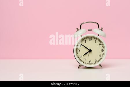 Réveil en métal blanc sur une table blanche, de dix à huit heures du matin Banque D'Images