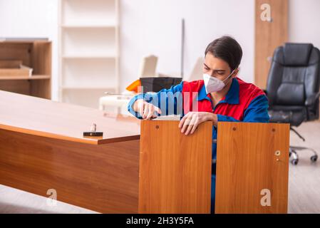 Jeune menuisier de sexe masculin travaillant au bureau pendant une pandémie Banque D'Images