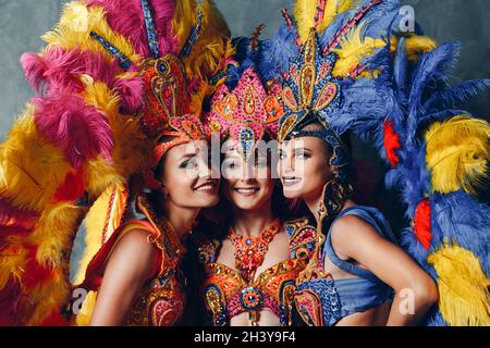 Trois femmes souriant portrait en costume brésilien de carnaval de samba avec plumage de plumes colorées Banque D'Images