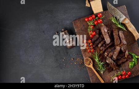 Morceau de bœuf rôti coupé en morceaux sur une planche à découper brune vintage.Délicieux steak Banque D'Images