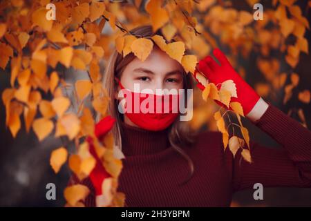 Jeune femme active en gants rouges et masque facial à parc d'automne Banque D'Images
