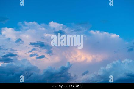 Un cadre plein de ciel surréaliste avec de beaux nuages colorés de bleu, gris blanc et lumineux rose pâle, rétroéclairé de la lumière du soleil Banque D'Images