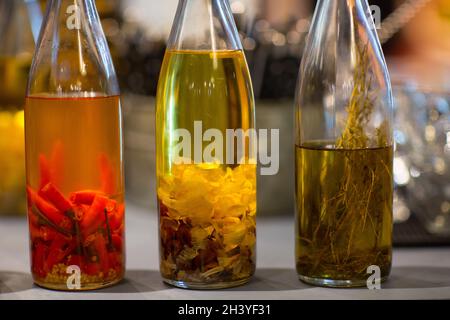 Huile d'olive en bouteille avec ail, poivre rouge et romarin sur la table de la pizzeria Banque D'Images