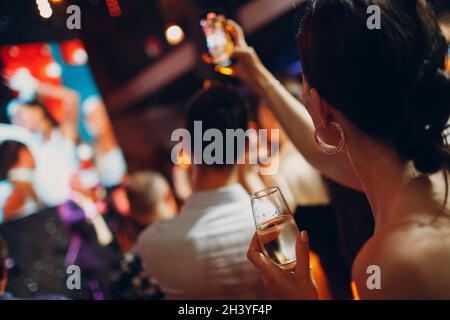 Vue arrière femme tenant un verre de champagne frais embué à la main à la fête Banque D'Images