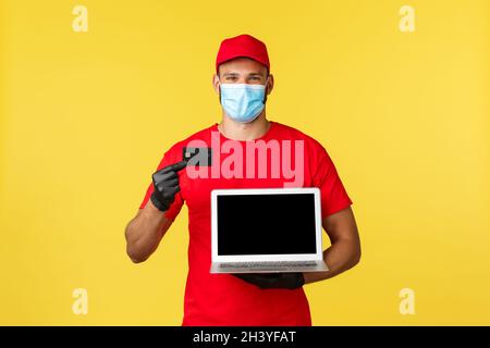 Covid-19, achats sécurisés, livraison express et concept de suivi des commandes.Coursier souriant dans un masque médical, uniforme, montrant le crédit c Banque D'Images